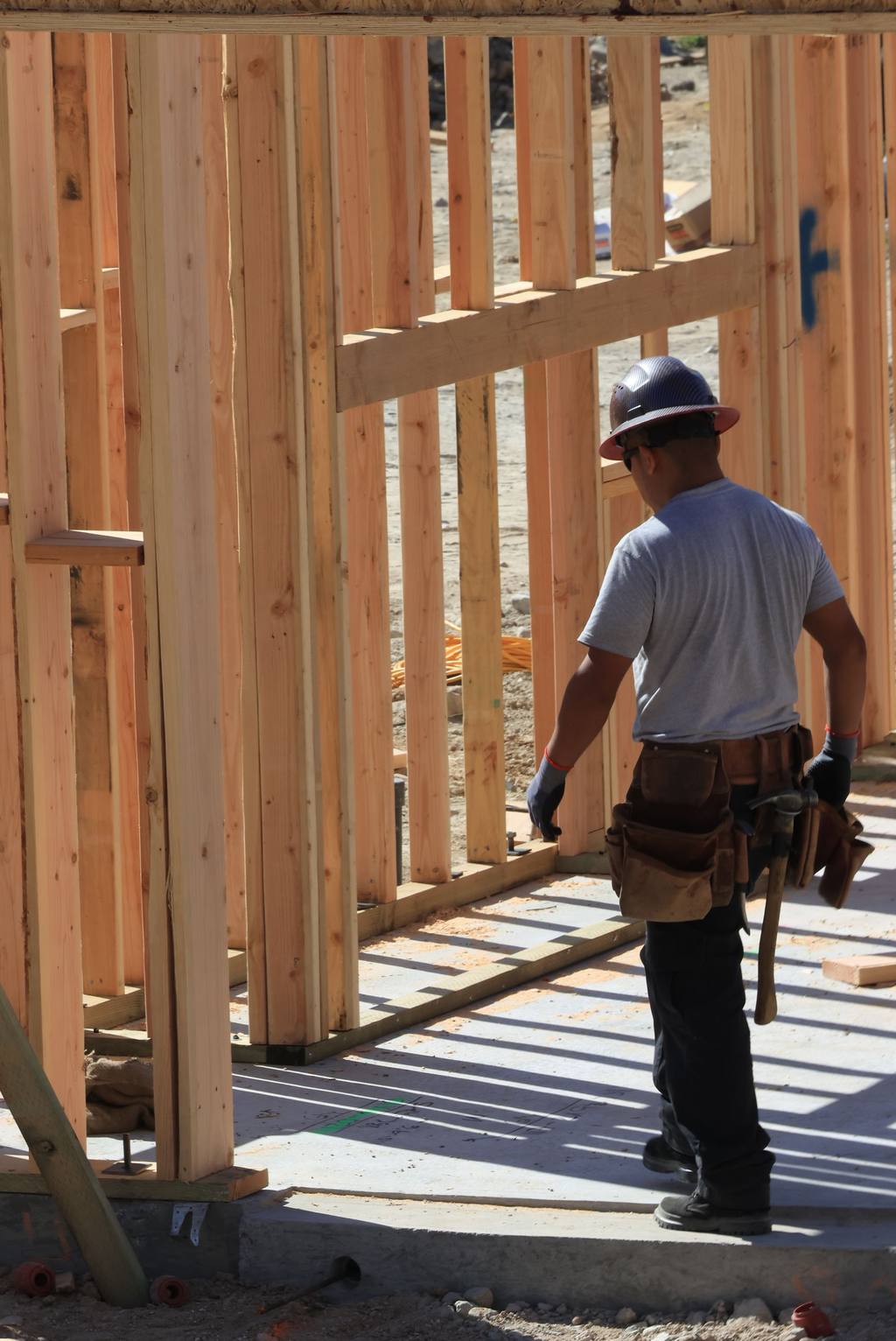 Construction worker with tools and safety helmet building a timber-frame house